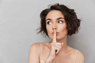 Poster - Close up of a worried young woman showing silence gesture