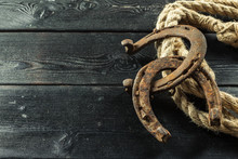Old Horseshoe And Rope On Wooden Boards