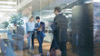 © Gorodenkoff - Businessman and Businesswoman Walking Through Glass Hallway, Discussing Work and Using Tablet Computer. Busy Corporate Office Building with Many Workers.