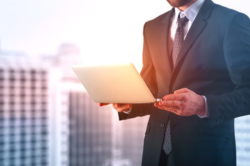 Canvas Print - Young businessman using laptop in city