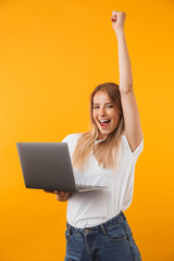Wall Mural - Portrait of a joyful young blonde girl holding laptop