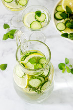 Lemonade With Cucumber, Lemon Balm And Thyme In A Transparent Jar On The Background Of Plates With Ingredients.