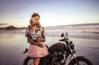 sensual couple cuddling on motorcycle on ocean beach during beautiful sunrise