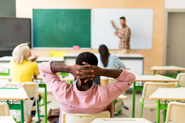 Wall Mural - back view of relaxed african american student sitting at classroom during lesson