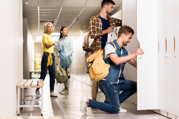 Wall Mural - Young students spending time together in college corridor