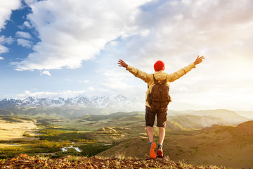 Happy tourist man raised arms against sunset mountains