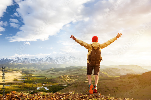 Foto Happy tourist man raised arms against sunset mountains