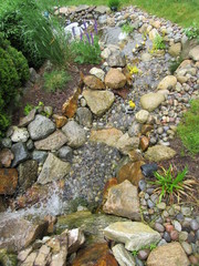 A man made waterfall and stream leading to a Koi fish pond at the bottom 