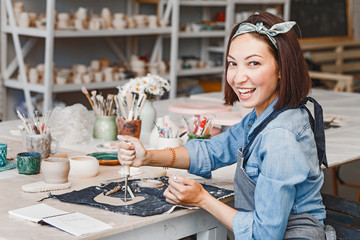 Workshop of clay pottery ceramic, woman decorating dishware pot