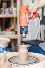 Wall Mural - Artist drying just made cly jar on a pottery wheel using professional dryer