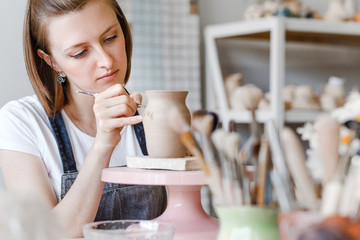 Workshop of clay pottery ceramic, woman decorating dishware pot