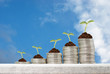 Business concept with stacks of coins with growing plants against blue sky background