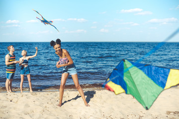 selective focus of multicultural friends with kites spending time on sandy beach together