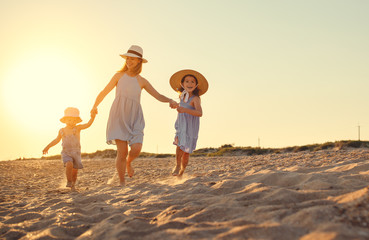 Wall Mural - Happy family mother and children on beach by sea in summer.