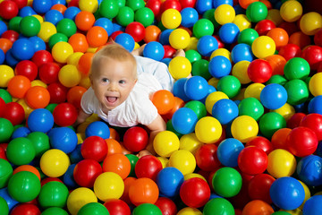 Cute toddler boy, child, playing in colorful balls in children playground