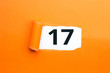 Zahl siebzehn - 17 verdeckt unter aufgerissenem orangen Papier
