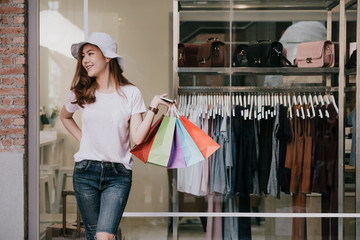 happiness, consumerism, sale and people concept - smiling young woman with shopping bags over mall background