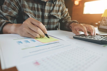 business, finance, tax and people concept - close up of man hands counting financial document with calculator and tax report form