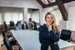 © bnenin - Portrait of a business woman with a team in meeting in background.