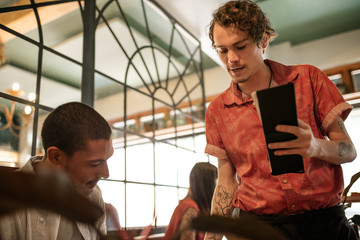 Waiter explaining the menu to a smiling restaurant customer