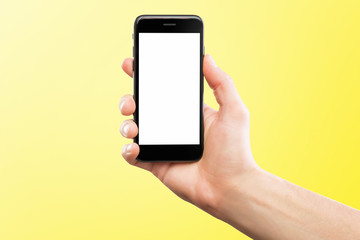 Male hand holding black cellphone isolated at yellow background.