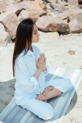 Wall Mural - high angle view of focused asian woman meditating with closed eyes in anjali mudra rT6y_vb! pose on yoga mat