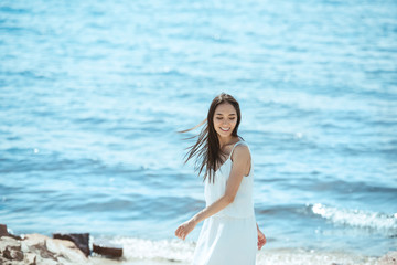 Wall Mural - smiling asian woman in white dress standing by sea during daytime