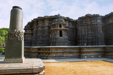 Garuda pillar on the left and Hoysaleshwara temple in the background, Halebidu, Karnataka. View from South.