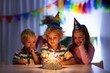 Kids birthday party. Children blow cake candles.