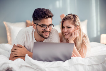 Wall Mural - Young couple with laptop in the bed.