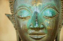 Close Up Of A Face Of An Ancient Copper Buddha Statue Outside Of The Hor Phra Keo Temple (former Temple Of The Emerald Buddha) In Vientiane, Laos.