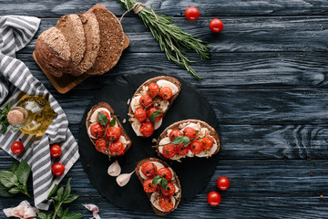 Wall Mural - Multigrain bread with mozzarella and baked tomatoes on on dark slate board