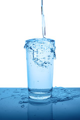 overflowing mineral water in transparent glass with drops and bubbles isolated over white, blue back