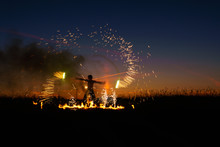 A Man With A Torch At Sunset. Fire Show And A Lot Of The Bright Sparks In The Night