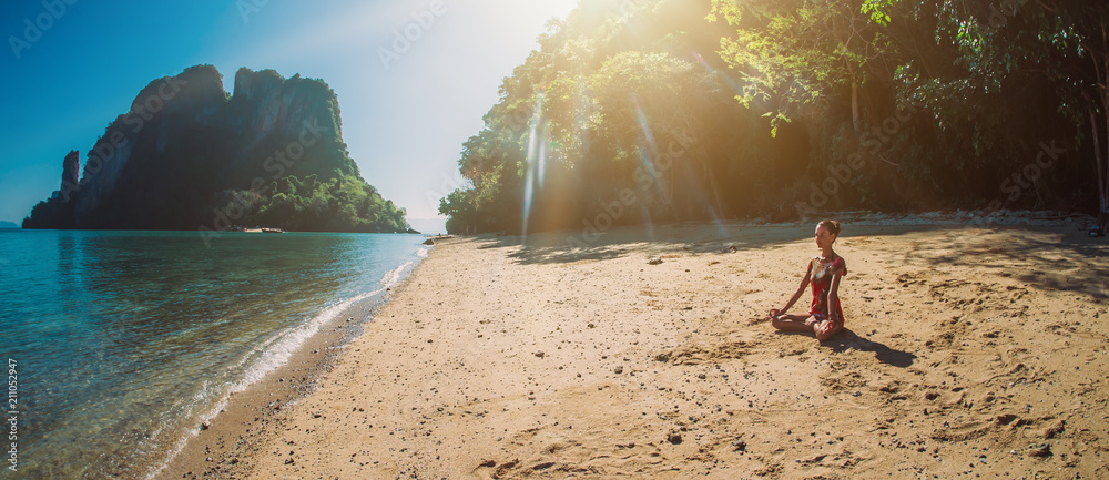 Fit woman relaxing and practicing yoga outdoors by the sea - obrazy, fototapety, plakaty 