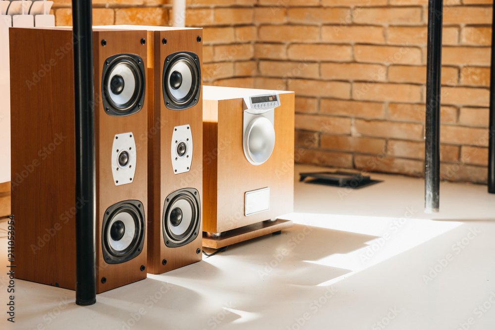 Musical stereo speakers and wooden subwoofer in the interior of a bright room. Musical concept. - obrazy, fototapety, plakaty 