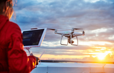 Wall Mural - drone quadcopter with digital camera operated by woman at sunset