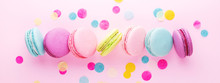 The Row Of Colorful Sweet Macarons On Pink Background Decorated With Confetti. Top View, Minimal, Banner.