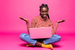 © F8  \ Suport Ukraine - Optimistic woman with beautiful smile using silver notebook, while sitting in lotus pose on the floor and throwing hands aside isolated over pink background