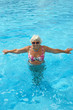 © vaz1 - Aged woman is doing spa exercises in bright blue water of pool.