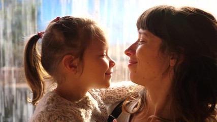 young mother holds hug and kiss her little kid daughter on hands - tender happy family portrait
