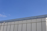 Fototapeta Na sufit - Facade of a concrete slab building on an angle against a blue sky, horizontal aspect