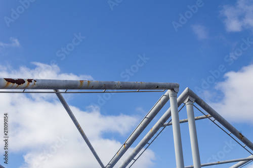 Fotografie, Obraz Abstract background of overhead pipes against a blue sky with clouds, horizontal
