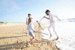 © goodluz - Family having fun writing messages on sandy beach