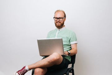 Wall Mural - Young bearded hipster man using laptop over white background