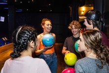 Cheerful Multi-ethnic Teenagers Talking While Holding Bowling Balls