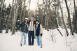 © Maskot - Full length of smiling friends standing against trees on snow covered field