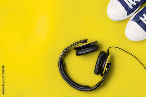 Fotografía A pair of new stylish sneakers and headphones on a yellow bright background