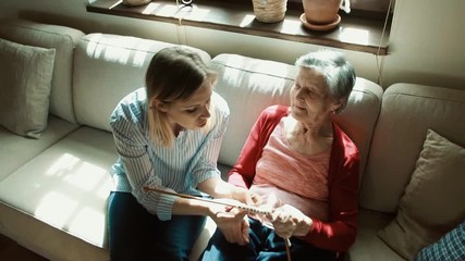 Wall Mural - Elderly grandmother and adult granddaughter at home, knitting. Top view.