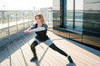 © WellStock - Young attractive fit and sporty woman in stylish black sportswear exercising during the workout on the big terrace on the rooftop on sunny day.